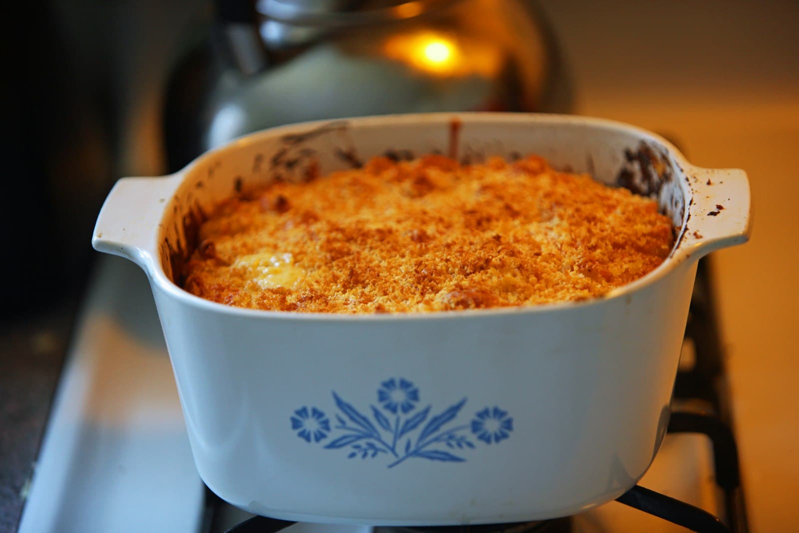 Baked mac and cheese with a golden breadcrumb crust in a white casserole dish on the stove