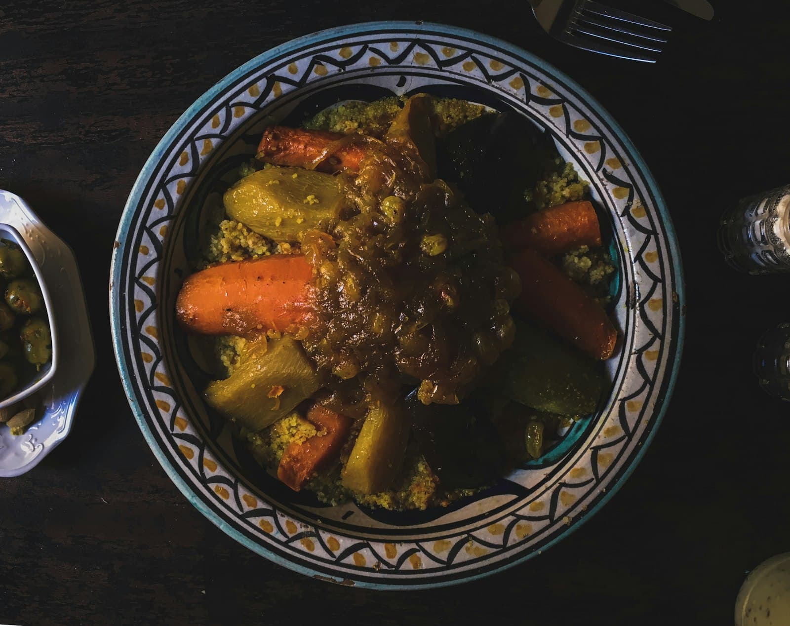 Moroccan couscous topped with carrots, squash, zucchini and caramelized onions in a hand-painted bowl