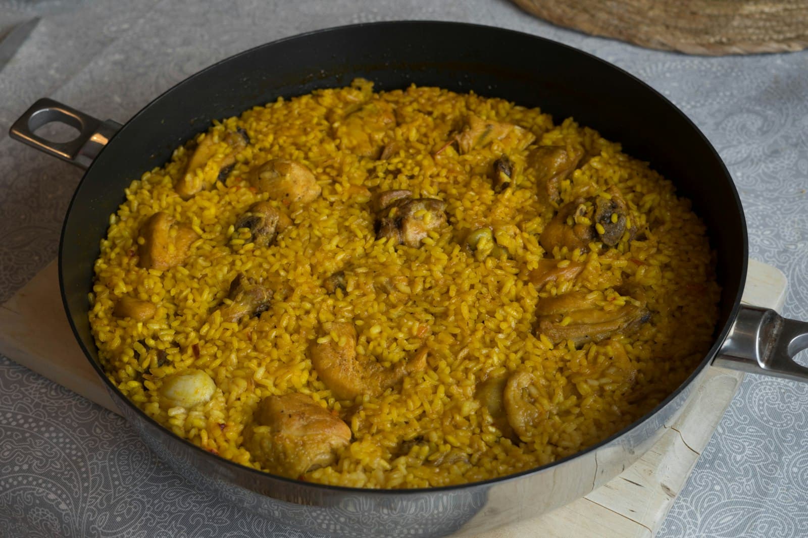Chicken paella with golden saffron rice and browned chicken pieces in a wide pan
