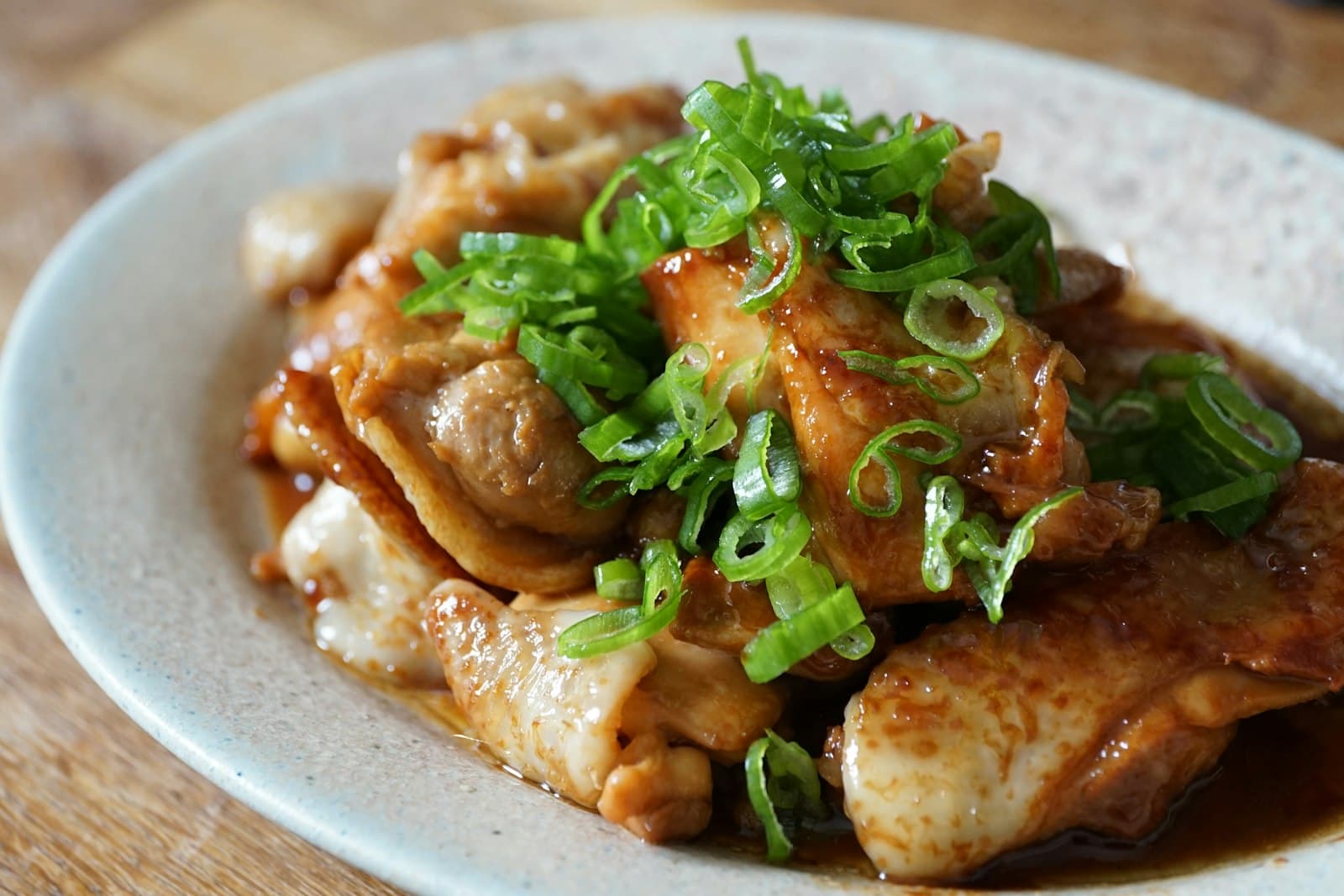 Glazed honey garlic chicken thighs topped with sliced green onion in a shallow bowl